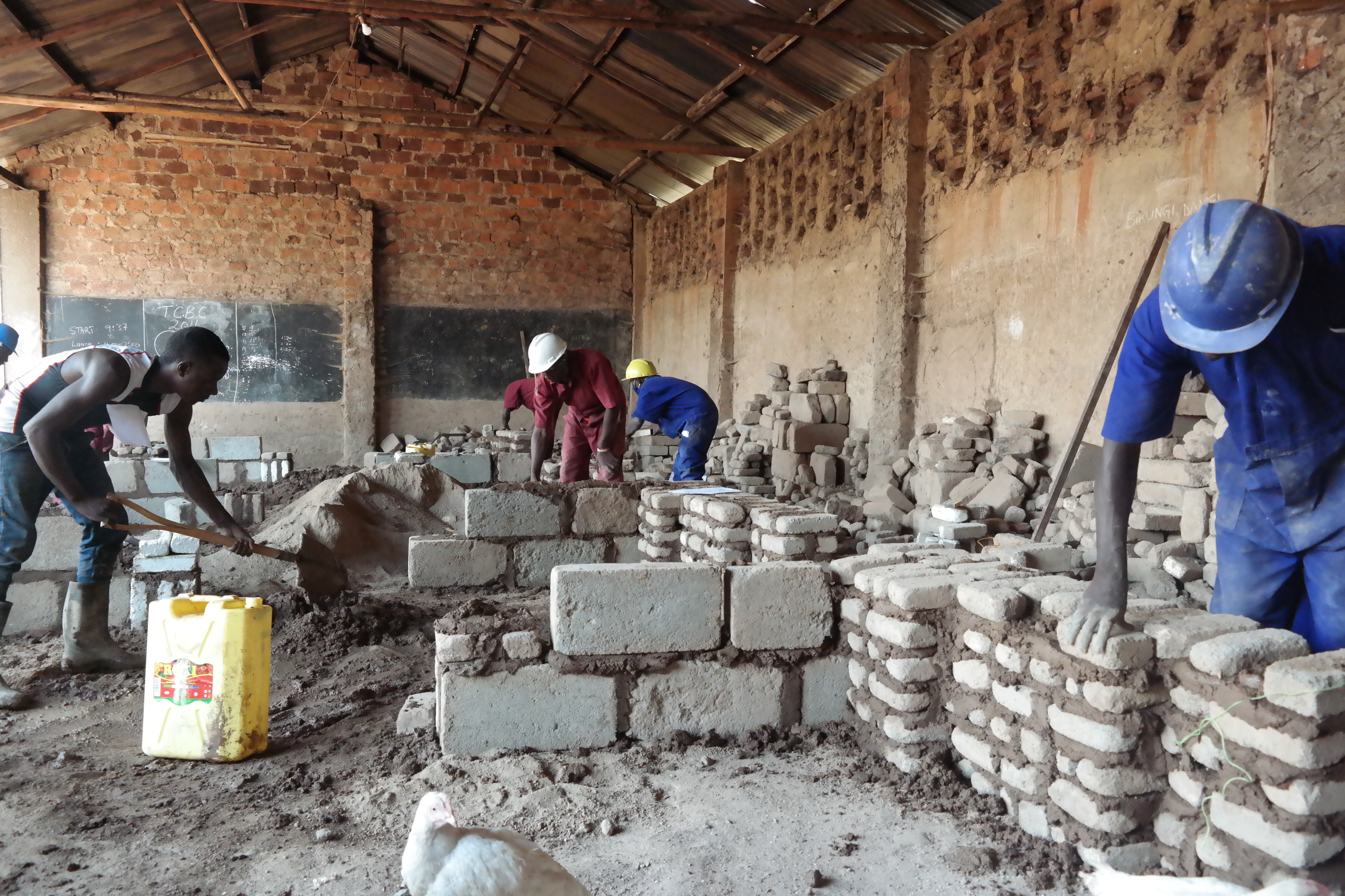 Students mixing mortar and laying blocks on the construction site